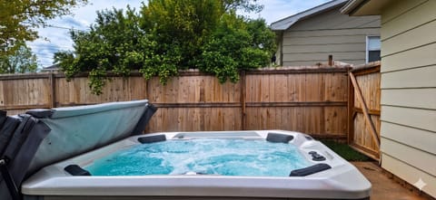 6-person hot tub with privacy fence and lush greenery in fenced backyard