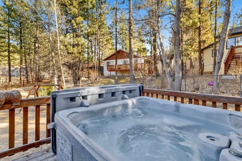 Private outdoor deck with a BBQ and a hot tub, surrounded by tall pines, perfect for relaxing under the trees after a day of adventure—enjoy peaceful forest views, fresh air, and a truly rejuvenating stay.
