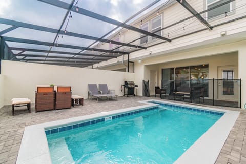 Step outside to a private pool area with a stylish screen enclosure that lets in sunlight while providing shade. Relax on contemporary lounge chairs atop the beautifully paved surface, perfect for unwinding in a serene atmosphere.