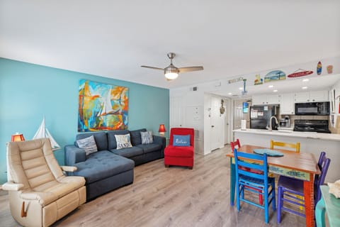 Your vibrant beach escape awaits with a bright living space featuring cozy seating, cheerful colors, and an open kitchen for memorable meals together.