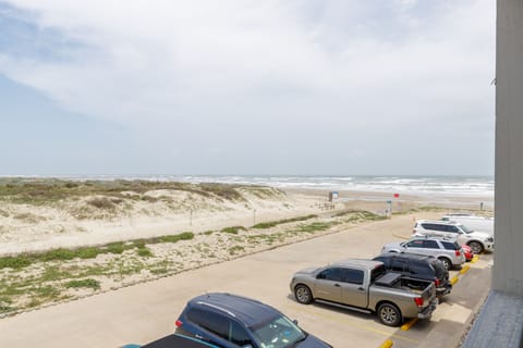 Beachfront property with convenient parking overlooking expansive sandy shores and ocean waves.