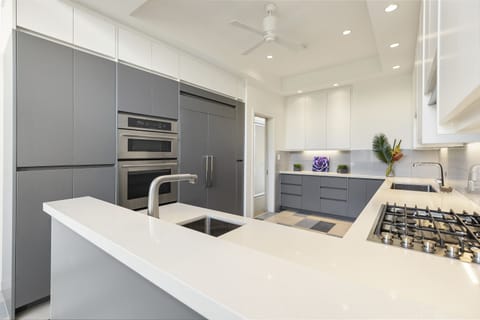 Prepare your favorite meals in the sleek gray-and-white kitchen featuring modern appliances and a gas cooktop.