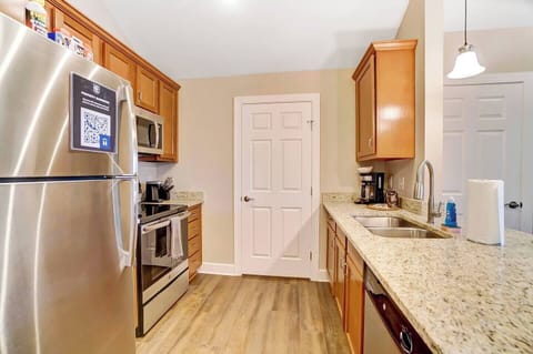 Kitchen features stainless steel appliances and granite countertops + lots of cabinet space full of kitchenware.