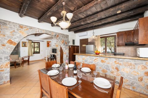 Open-plan living room with sofa, dining area, kitchen, indoor pool, ornamental fireplace, A/C, WiFi internet, and satellite TV