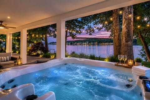 Waterfront hot tub with sunset views, string lights, and spa-like ambiance