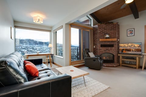 Cozy up by the crackling fireplace in your mountain retreat, where floor-to-ceiling windows frame stunning winter vistas from your comfortable leather seating.