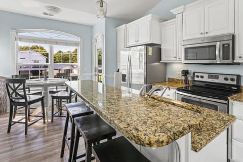 Sunlit kitchen with granite island and cozy dining nook