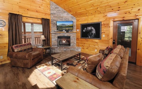 Cozy living room with stone fireplace, bear decor, and rustic furnishings.