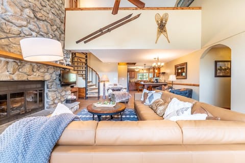 Spacious living area featuring large wood burning fireplace, ample seating and sweeping mountain views.
