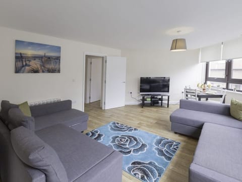 Living room with large grey sofa, blue patterned rug, wall art, and dining nook – Castle 6 - Southampton