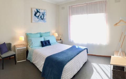 Bedroom with Queen bed, bedside drawers, Hanging racks and clothing shelf.
