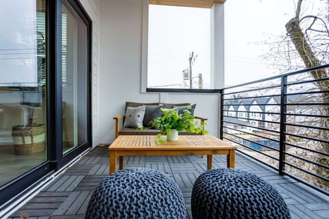 Balcony patio with outdoor sofa, wood coffee table, and wicker ottoman poufs