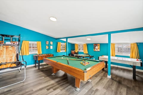 Game On Central! 🎮🌟🏡 - A fully equipped game room featuring a pool table, foosball, poker table, and basketball setup for a diverse and thrilling leisure experience.