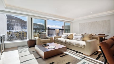 Sink into plush seating as you gaze out at snow-dusted peaks through expansive windows, where mountain tranquility meets refined comfort in your private retreat.