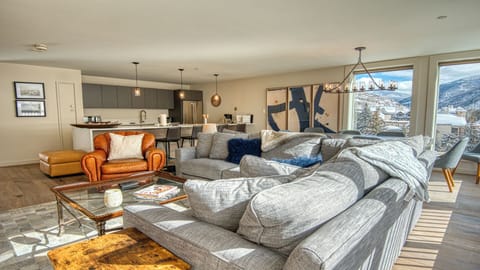 Unwind in your open-concept living space with cozy seating, modern kitchen access, and breathtaking mountain views framing your entire stay in natural light and alpine beauty.