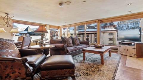 Sink into plush leather seating and take in breathtaking alpine views from your cozy living room, where rustic charm meets mountain elegance and every window frames a winter wonderland.