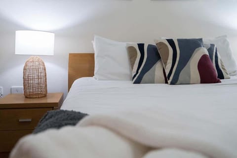 Sleep in comfort with our cozy bed, soft linens, and stylish pillows, all lit by the warm glow of a bedside lamp. A relaxing space for a memorable stay. 😊