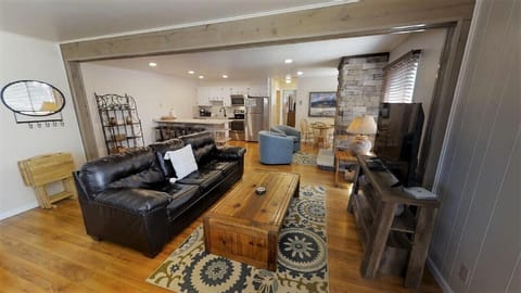 Unwind in your spacious open-concept living area, where rustic wood floors, a cozy leather sofa, and a stone fireplace create the perfect mountain retreat for relaxing after a day of adventure.
