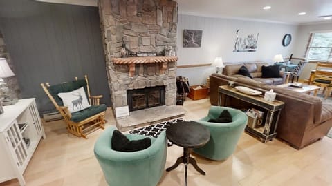Settle into plush seating by the stone fireplace, where rustic charm meets modern comfort in your mountain retreat.