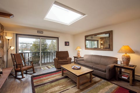 Unwind in your welcoming living room with a cozy fireplace, comfortable seating, and natural light streaming through the skylight above.