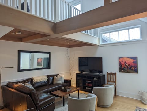 Bright, open living area with NEW leather sectional +large flat-screen TV