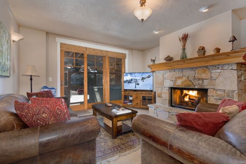 Living Room with plush leather sofas, gas fireplace, 55" LG smart tv, and private hot tub patio access