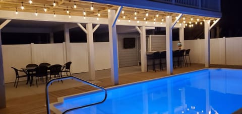The outdoor oasis - heated pool, tiki bar, dining area, and TV.