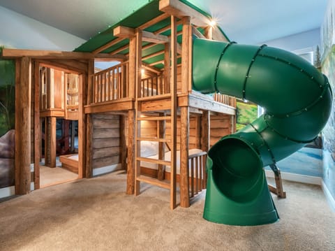 - Adventure awaits in this treehouse style bedroom with a green slide  
- Built-in wooden bunk beds bring playful cabin vibes to the space  
- Indoor slide adds excitement and fun for children of all ages