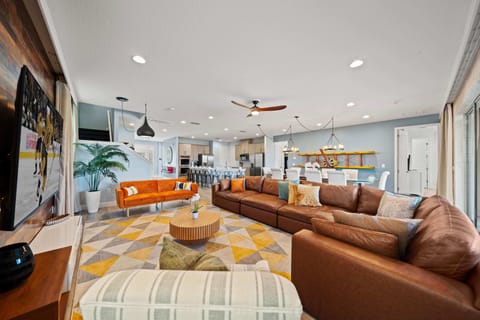 - Spacious living room with modern sectional and wood accent wall  
- Bright open floor plan flows into dining and kitchen areas  
- Large smart TV and cozy seating make it ideal for family nights