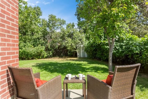 Private backyard lounging area. Apple tree and grapes on the right, and the backyard extends the length of the house to the left with lush vegetation throughout. _