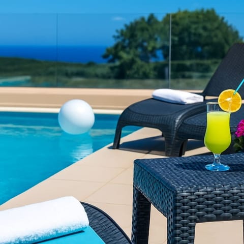 Exterior Lounge with Poolside Charm – Comfortable outdoor sitting area overlooking the shared pool between two properties, perfect for relaxing moments.