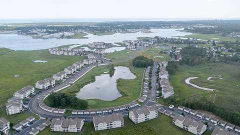 9405 Pettinaro Drive - Aerial Community View - High-angle aerial view of the Bethany Bay neighborhood and surrounding waterways, showcasing the layout of the community pond and nearby homes.