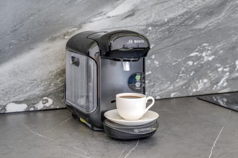 A modern coffee maker placed on a gray marble countertop. The setup is convenient and stylish for coffee enthusiasts.