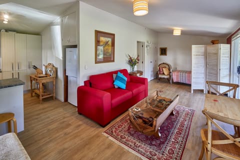 Red settee is comfortable double pullout divan. Cottage has heatpump/AC