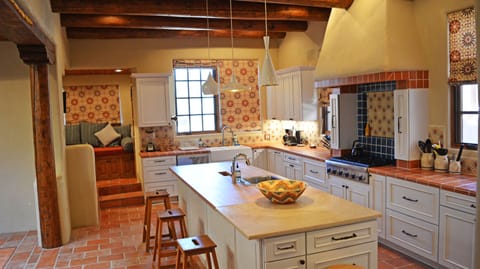 Reverse view of kitchen with alcove in back left, featuring large window seat, computer/task desk and swing mounted TV (unseen) facing into alcove