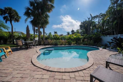 Your private tropical oasis awaits with sparkling pool surrounded by swaying palms and comfortable seating areas.