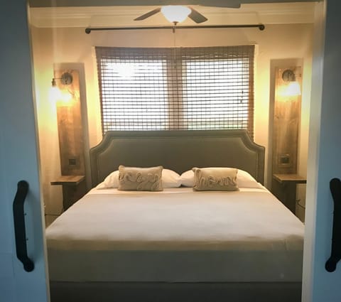 Bedroom boasts king memory foam bed with ceiling fan, separate window AC unit and open closet with hangers