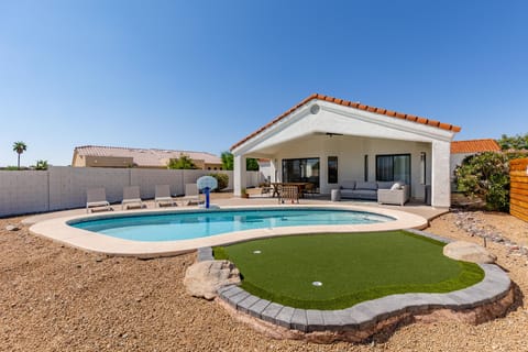Sparkling heated pool, putting green, fire pit, sun loungers, BBQ, cornhole, and outdoor patio furniture, plus dining area.