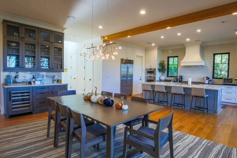 The butler's pantry features a wine refrigerator, sink, gorgeous quartz counters & backsplash and glassware.