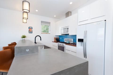 Kitchen with oven, microwave, coffee maker, refrigerator. Fully stocked with dishware and cookware.