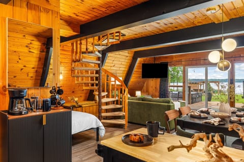 A warm and open living space with wood interiors, spiral staircase, and large sliding doors showcasing lake views.
