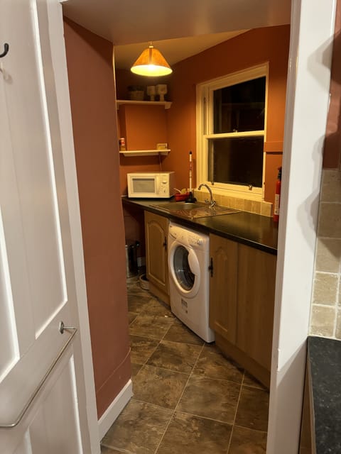 Kitchen annex with upright fridge, clothes washer, and microwave