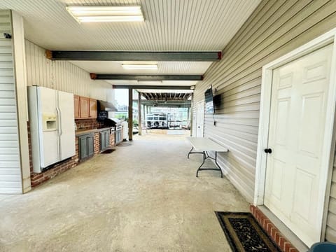 Outdoor kitchen area with grill, refrigerator, TV, sink. Bathroom downstairs