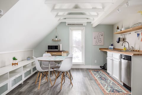 Bright kitchen w/ vaulted ceilings, open shelving & a cozy dining nook under exposed beams.