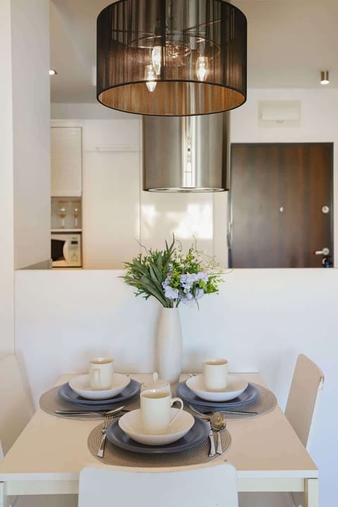 A well-lit living room with a dining area, light hardwood floors, and stylish decor
