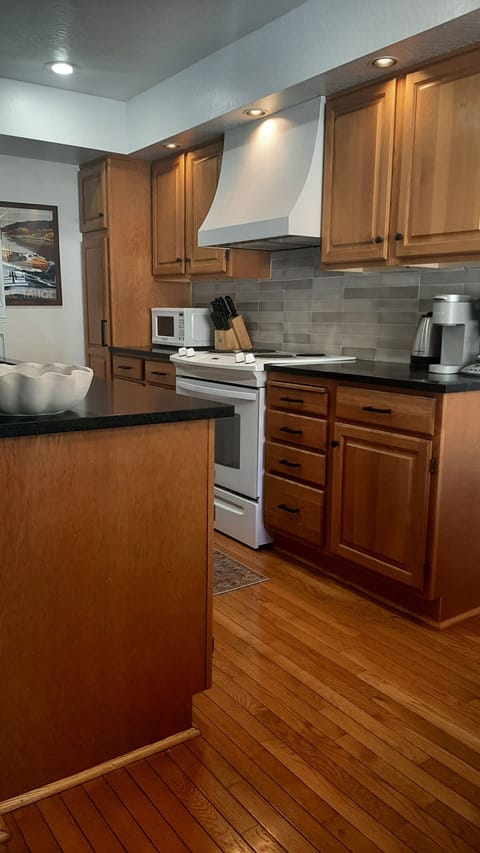 Updated Kitchen with stone counters and tile backsplash with custom hood.