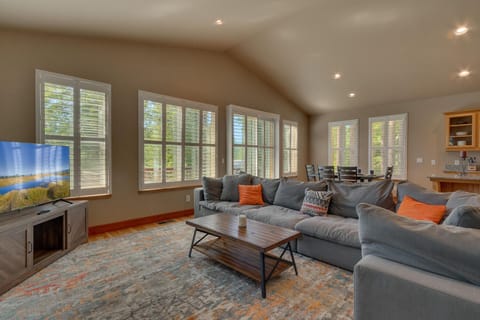 - Spacious living room with natural light and views  
- Large sectional sofa and flat-screen smart TV  
- Open layout connects to dining and kitchen areas