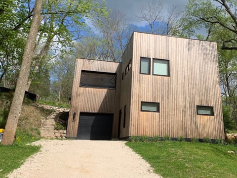 The modern new construction house is situated on a hill, with rustic wood siding