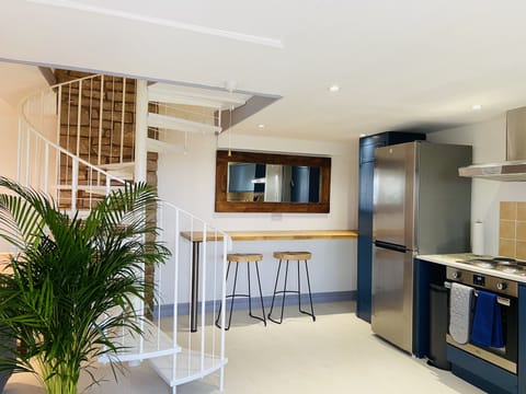 The open plan kitchen with breakfast bar and spiral staircase leading upstairs.