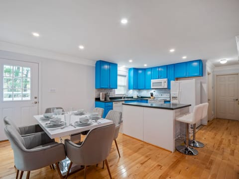 Open concept living area with 2 barstools, island has a bar for knee space